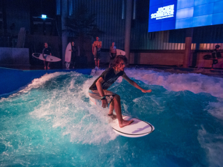 Ein Mann surft auf der stehenden Welle in der Jochen Schweizer Arena während der Pure Surf Night