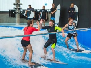 Drei Menschen surfen auf der Indoor Welle