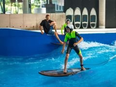 Ein Kind mit Helm surft auf der Indoor welle in der Jochen Schweizer Arena
