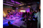 ThumbnailEin DJ legt Musik auf und viele Besucher stehen und sitzen im Welle-Bereich der Jochen Schweizer Arena und blicken auf die stehende Welle während der Pure Surf Night. 