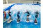 ThumbnailIndoor-Surfen für Kinder in der Jochen Schweizer Arena: Sechs junge Teilnehmer stehen lachend mit Surfboards auf der stehenden Welle und halten sich an einer Trainingsstange fest.