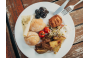 ThumbnailEin Teller mit Semmeln, Gebäck, Kartoffel Wedges, Käse, Tomaten, Beeren, Sprossen und Aufstrich