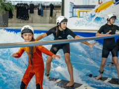 einige Kinder surfen gerade das erste Mal auf der stehenden Welle der Jochen Schweizer Arena