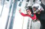 ThumbnailIndoor-Flugerlebnis für Kinder in der Jochen Schweizer Arena: Ein strahlender Junge im roten Anzug fliegt im Windtunnel, begleitet von einem Instruktor mit weißem Helm.