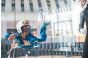 ThumbnailIndoor-Skydiving für Kinder in der Jochen Schweizer Arena: Ein lachendes Kind im blauen Fluganzug schwebt im Windkanal, beobachtet von einem Instruktor im schwarzen Anzug.