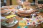 ThumbnailKindergeburtstag in der Jochen Schweizer Arena: Ein Marmorkuchen wird angeschnitten, umgeben von bunten Servietten, Gläsern und Kinderhänden an festlich gedecktem Tisch.