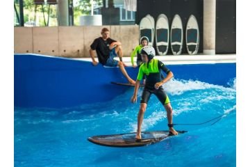 Ein Kind mit Helm surft auf der Indoor welle in der Jochen Schweizer Arena