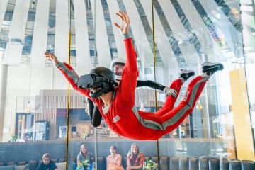 zwei Menschen fliegen im Windkanal in der Jochen Schweizer Arena, einer davon hat eine VR Brille auf.